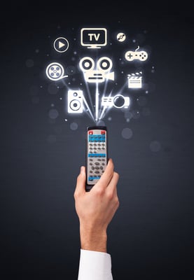 Hand holding a remote control, media icons coming out of it